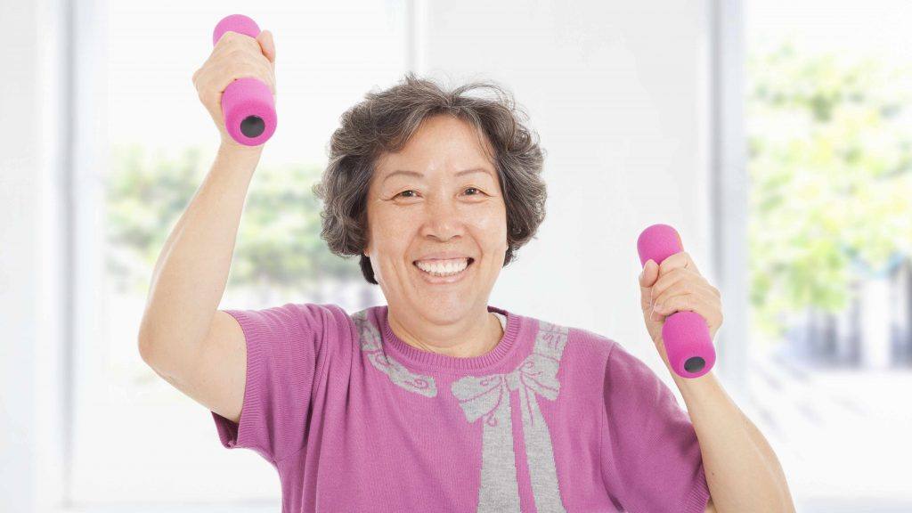 uma mulher idosa sorridente, fazendo exercícios com halteres