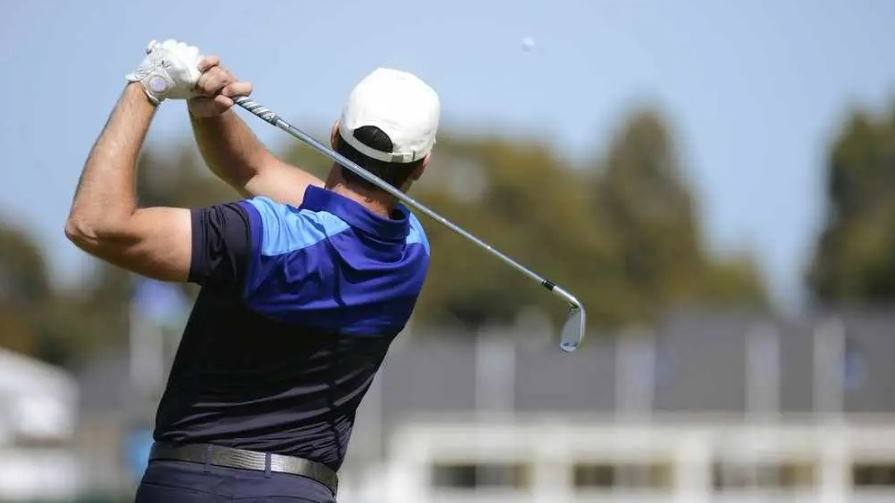 um golfista fazendo um swing e acertando uma bola de golfe
