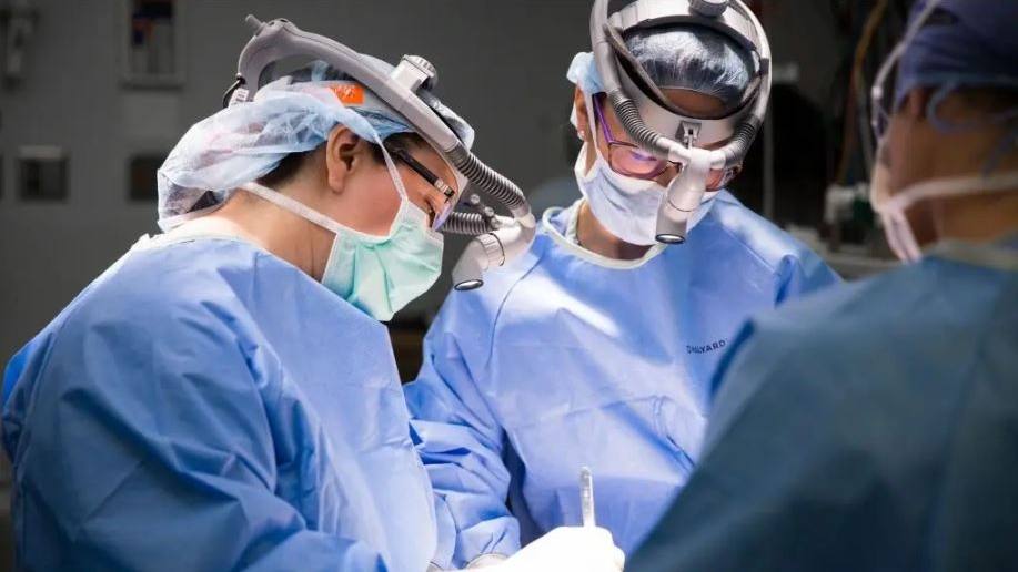 três cirurgiões realizando cirurgia na sala de cirurgia