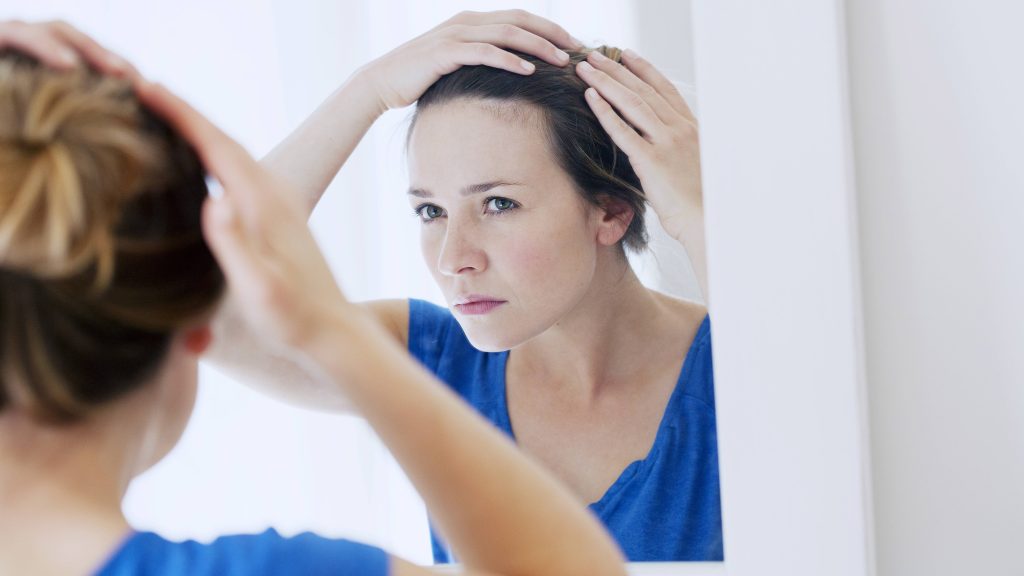 Uma mulher examina a linha do cabelo.