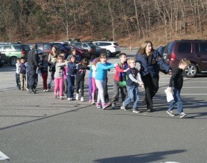 photo of children walking in parking lot with adult
