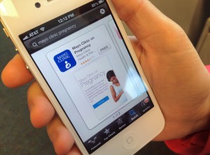Person's hand holding iPhone with image of Mayo Clinic Pregnancy App