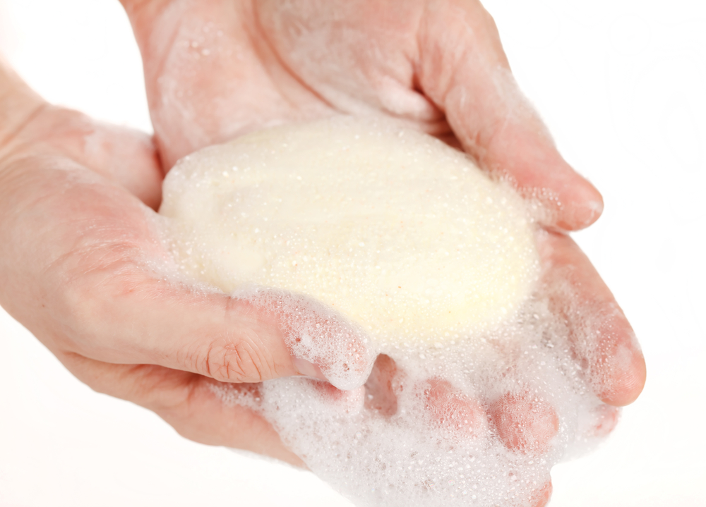 Two soapy hands holding an oval bar of soap