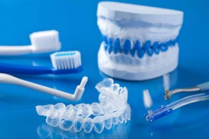 dentures, toothbrushes, tooth whitening trays, water pic on blue background