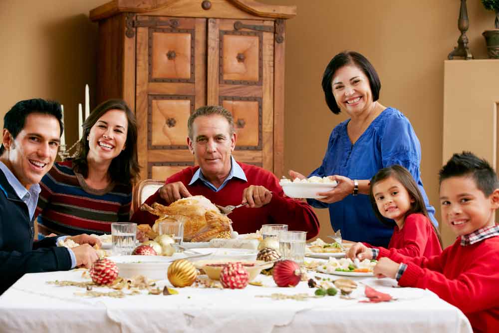 multi-generational Latino family at holiday dinner table with a turkey