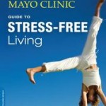 Mayo Clinic Stress-Free book cover with blue sky and woman in white exercise outfit doing a handstand