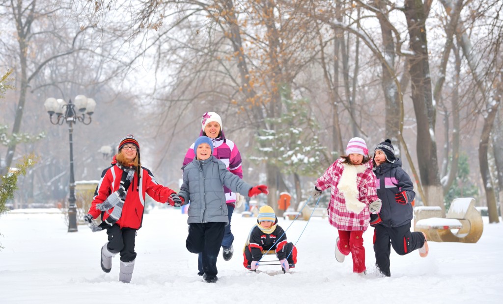 Children bundled up in winter clothes sledding and playing in the snow