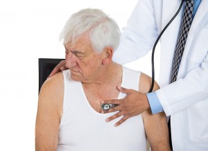 Elderly caucasian man in a white t-shirt with a physician listening to his chest with a stethoscope