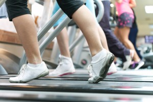 three or four women's legs running in tennis shoes on treadmills