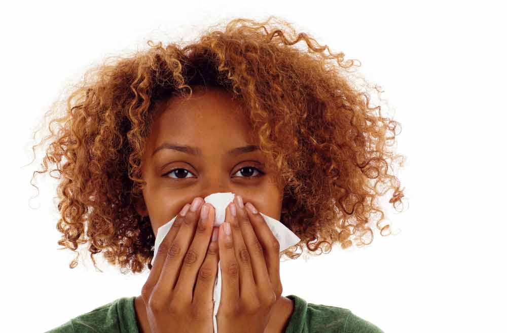 African American woman coughing and sneezing into tissue