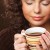 Woman holding cup of coffee with both hands and eyes closed.
