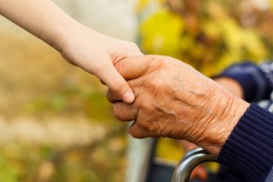 close up of child's hand holding an older adult hand with kindness