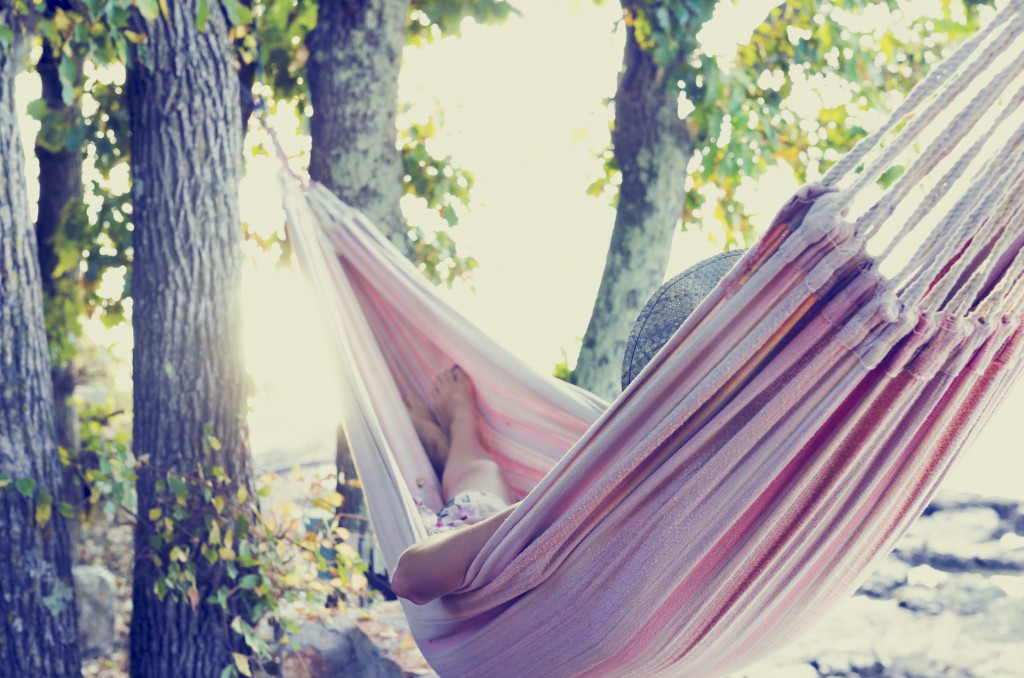 woman resting in a tree hammock in the shade on a hot summer day