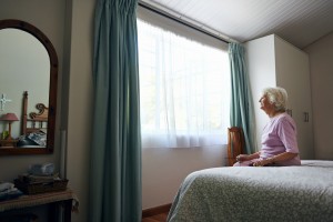 senior citizen, older woman sitting alone and looking out window