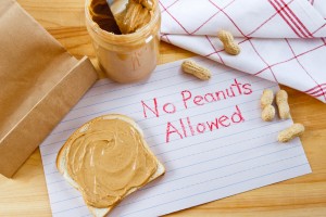 Letrero para alergia alimentaria que dice “no se permite el maní”, colocado junto a un frasco de mantequilla de maní
