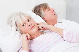 Un hombre ronca y la mujer se cubre los oídos para intentar dormir
