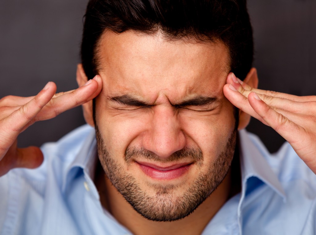 man pressing his hands to his temples because of a headache. 