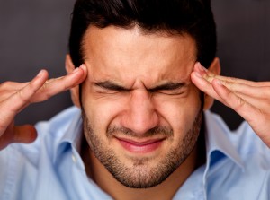 man pressing his hands on his forehead because of tension headache