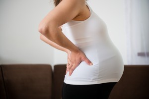 torso of pregnant woman with backache - holding back because of pain