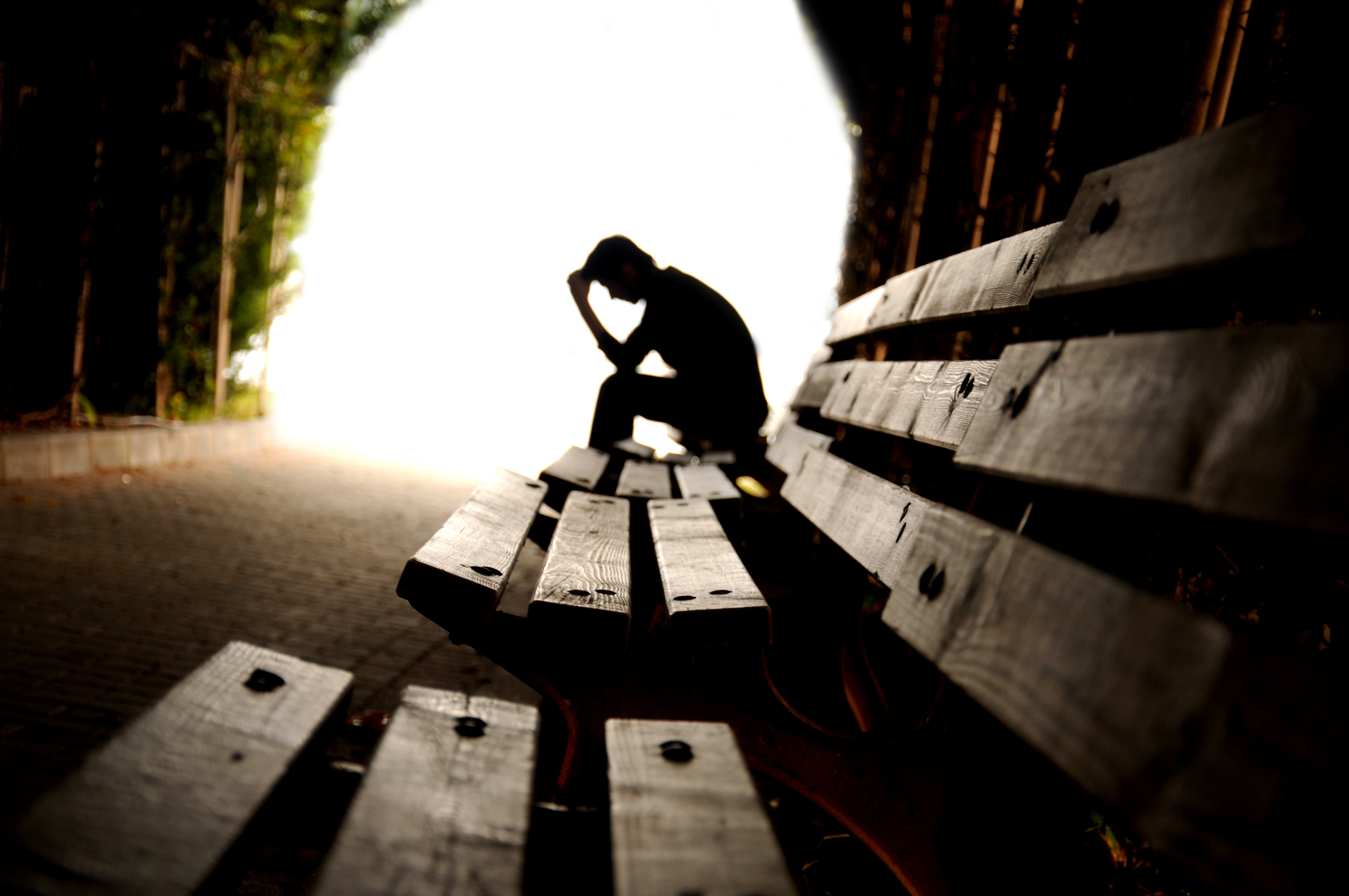 a lonely man sitting on a park bench