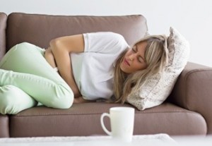 mujer recostada en el sofá con cólicos menstruales o dolor abdominal intestinal