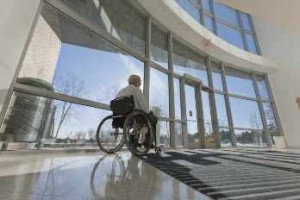 Hombre en silla de ruedas frente a la entrada adaptada del hospital