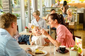 family eating in restaurant with mother feeding baby