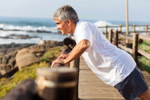 middle-aged man exercising and stretching near ocean
