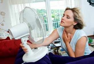 Mujer con calor y sudorosa se enfría con un ventilador