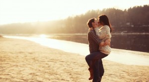 Young beautiful couple in love kissing on the beach on sunset.