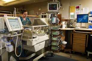 Una enfermera atiende a un neonato en la incubadora