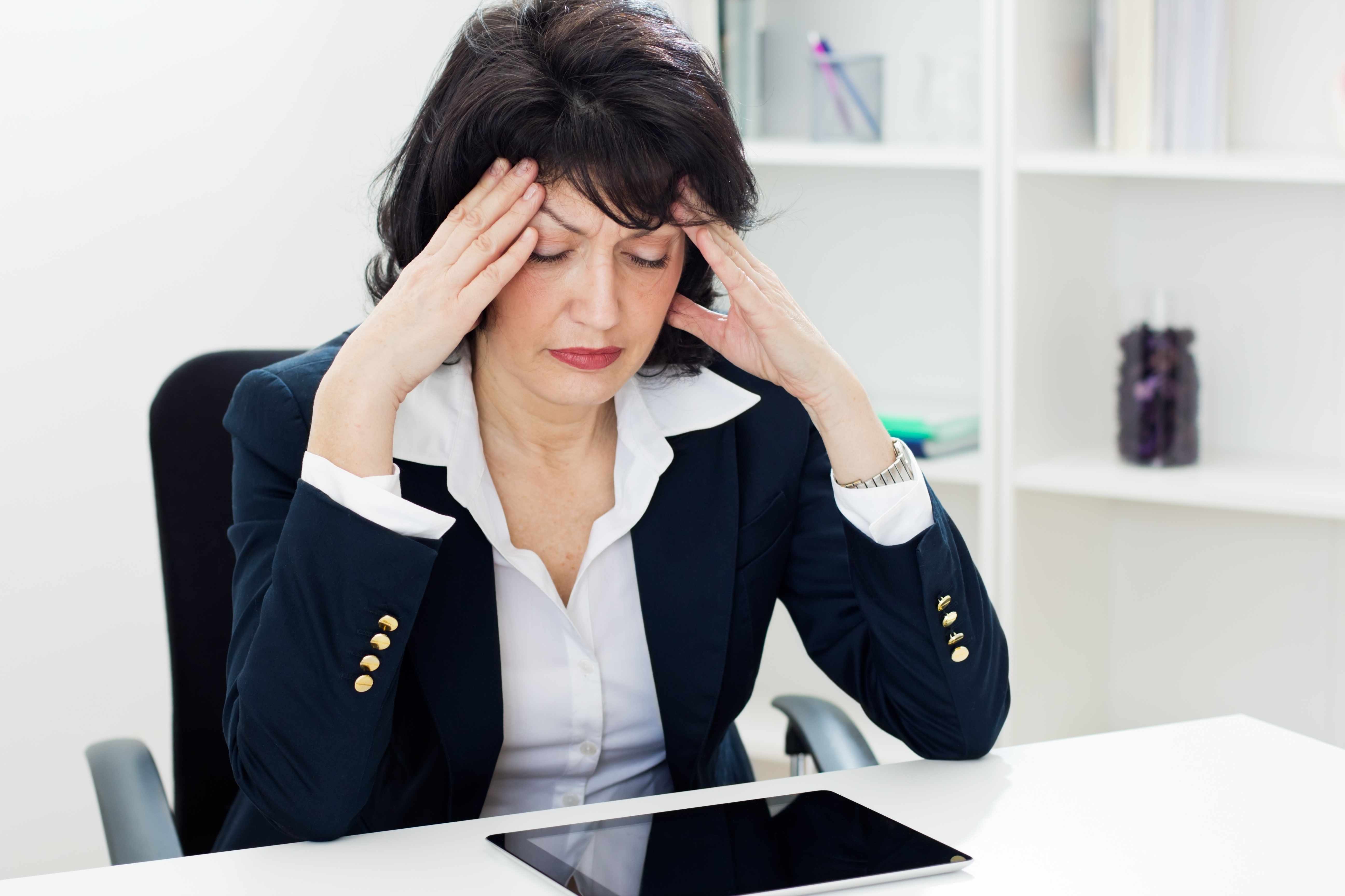 middle aged business woman at desk with headache