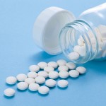 Small white aspirin pills spilling out of a glass jar
