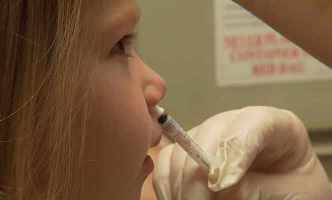 Una niña recibe la vacuna antigripal en rociador