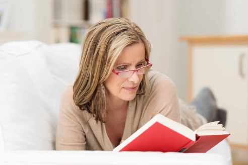 Mujer lee un libro con lentes de lectura