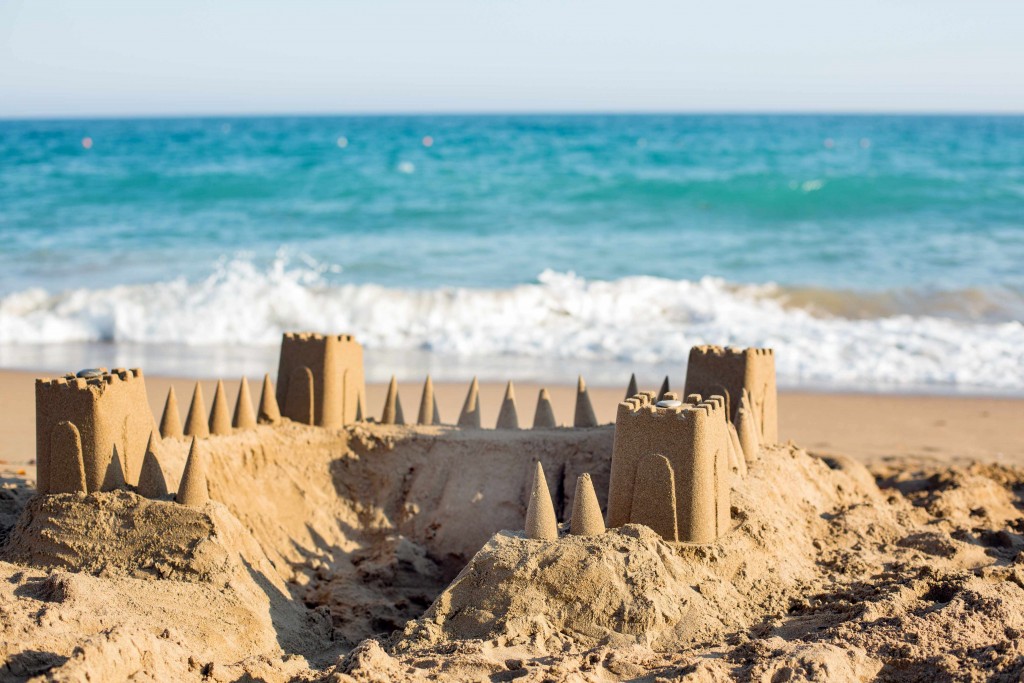 sandcastle on the beach with the ocean waves in the background