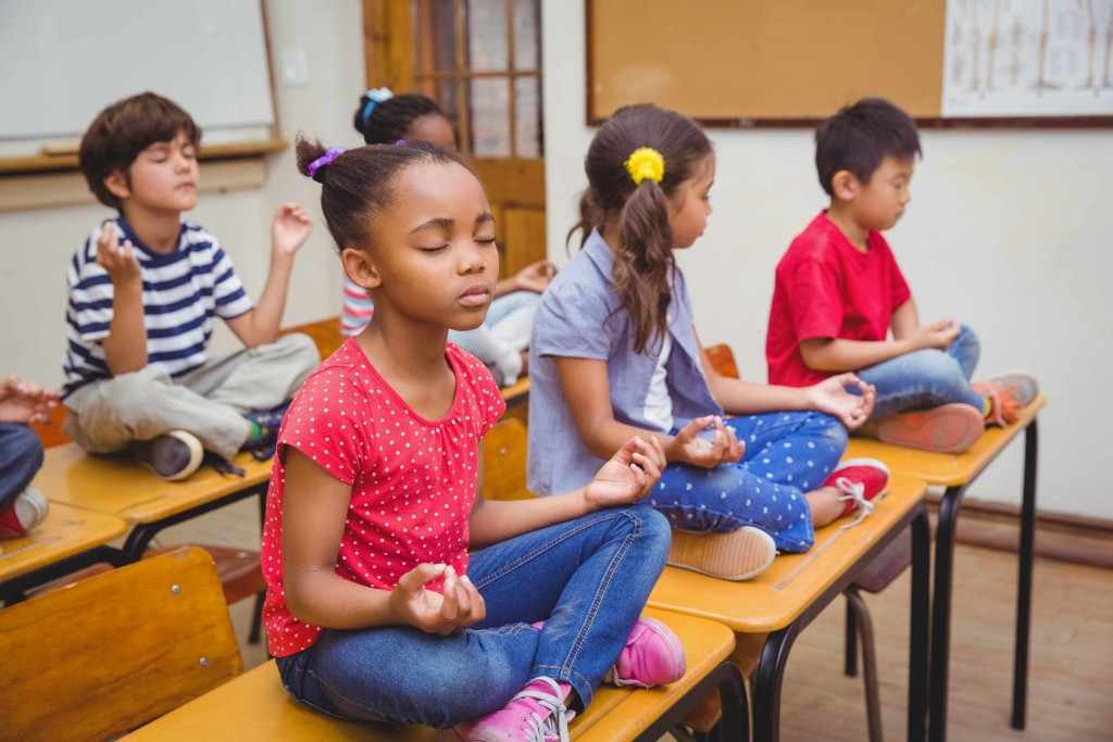 Unos estudiantes se relajan y meditan dentro del aula