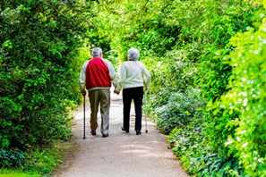 two senior citizens, elderly couple walking down a road or path