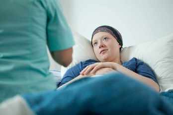 Una paciente de cáncer descansa en la cama con un pañuelo en la cabeza después de la quimioterapia