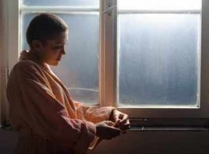 Paciente joven con cáncer piensa junto a la ventana 