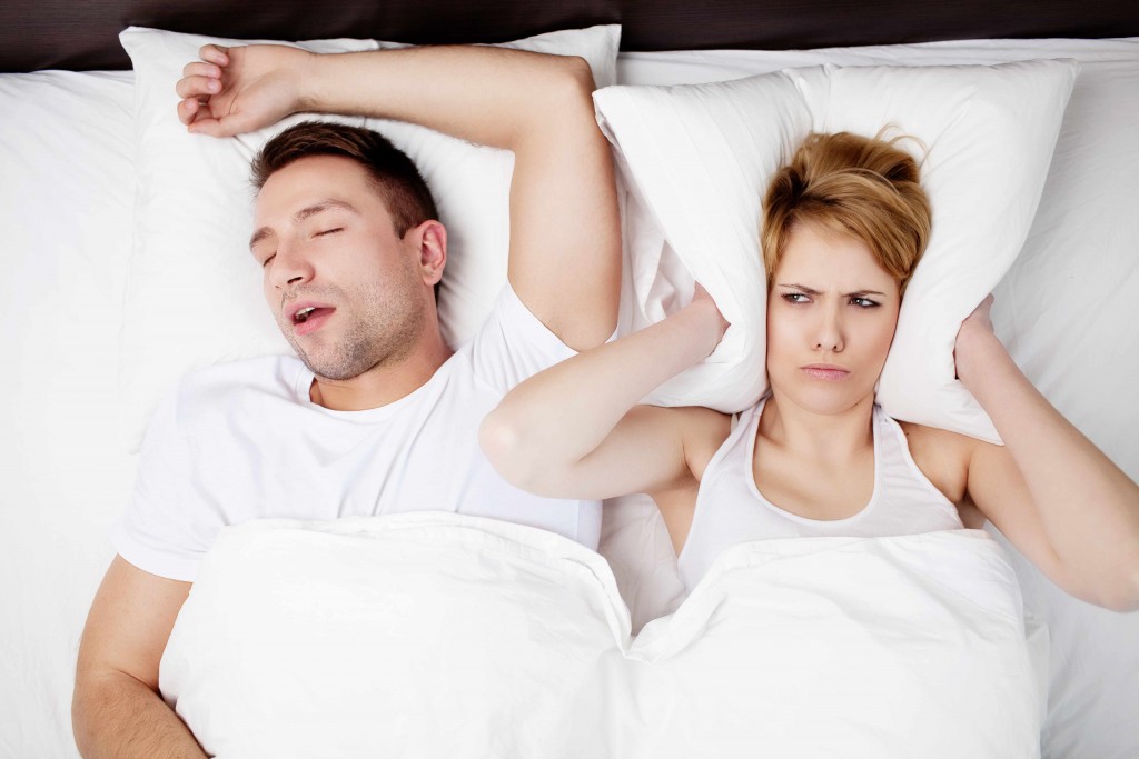 woman covering her ears from man snoring