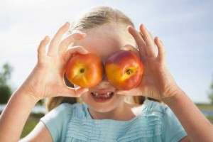 young girl, girl holding two apples over her eyes