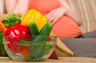 Una mujer embarazada come verduras sanas