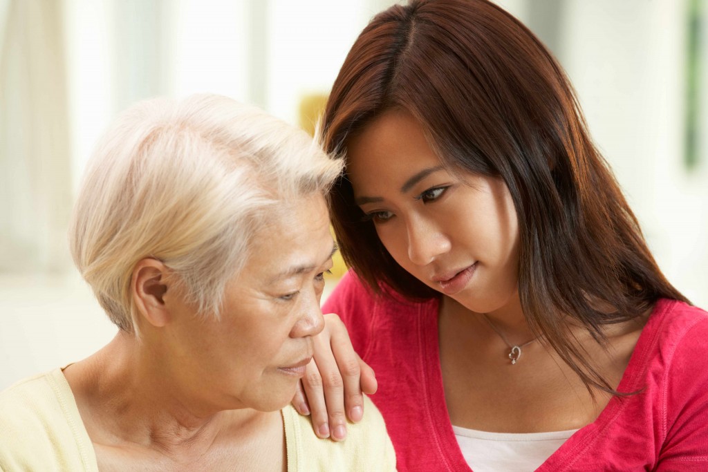 young Asian woman comforting older woman who is sad