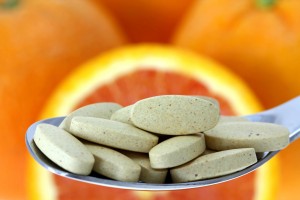 vitamin C supplements with oranges, citrus fruits in background
