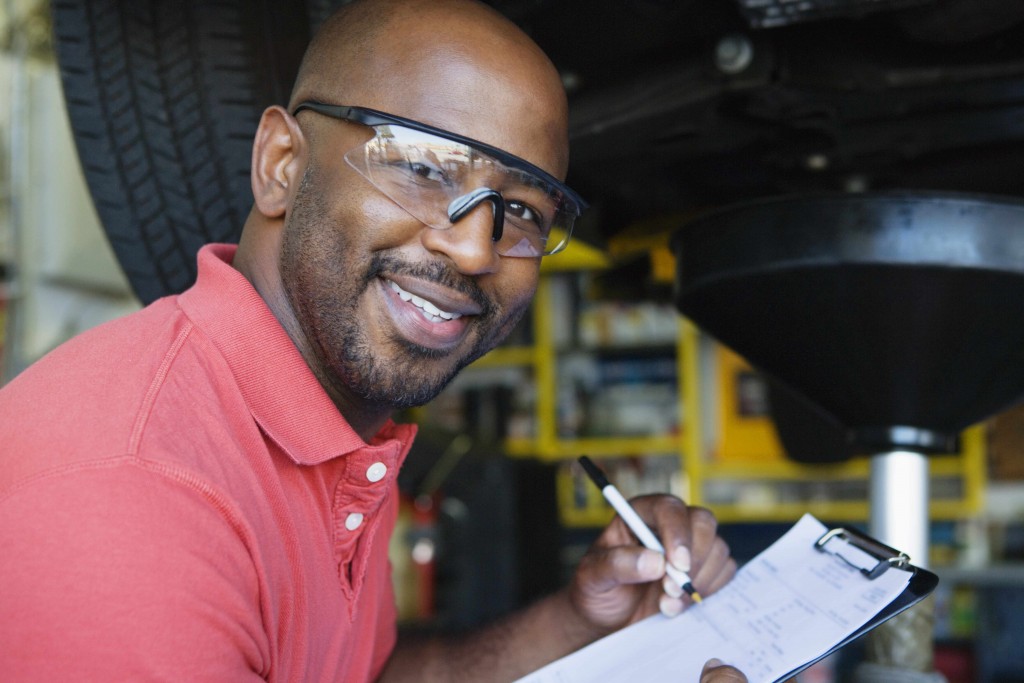 African-American man with working in garage wearing eye protection goggles