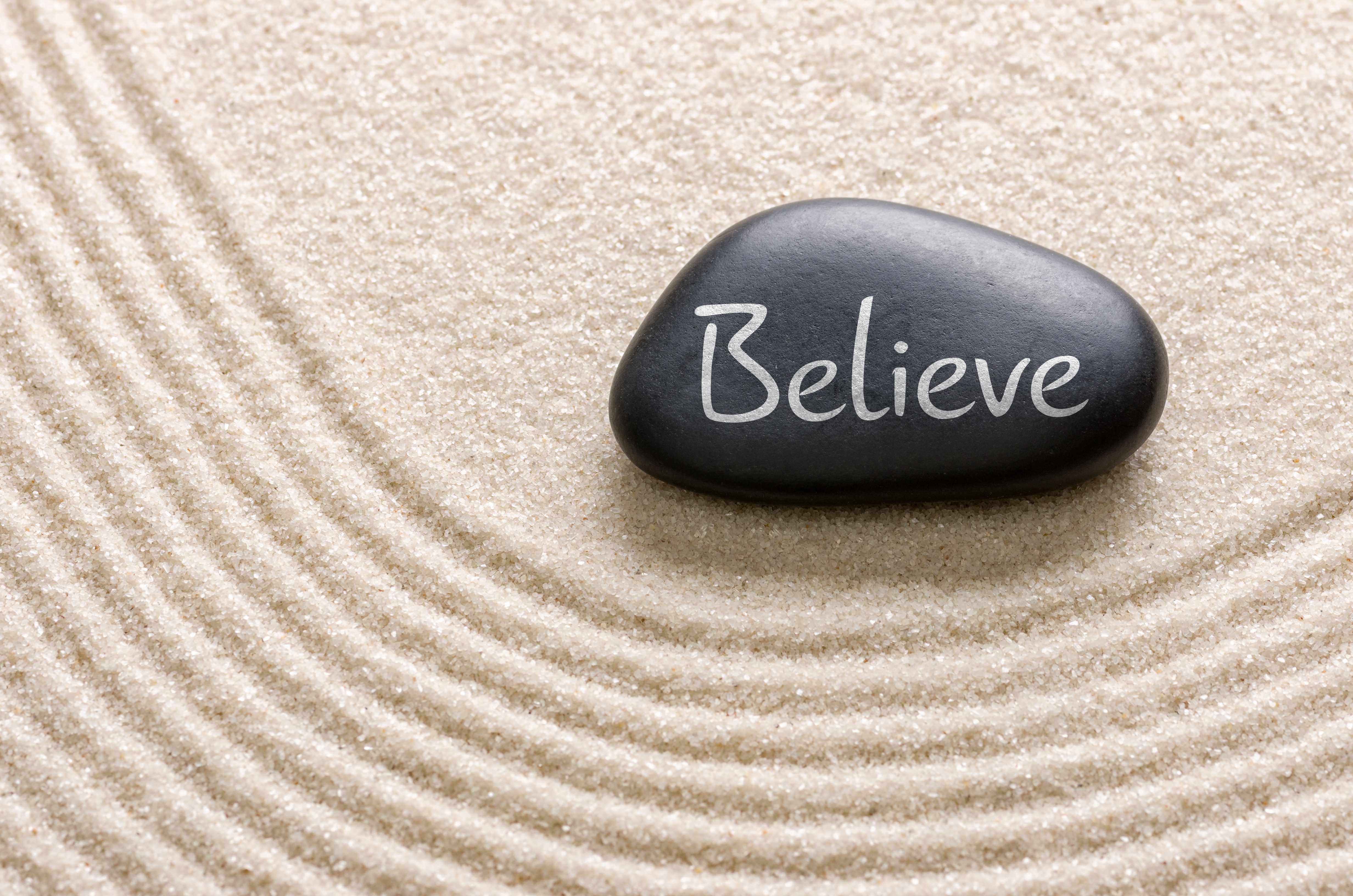 sand and stone with the word 'believe'