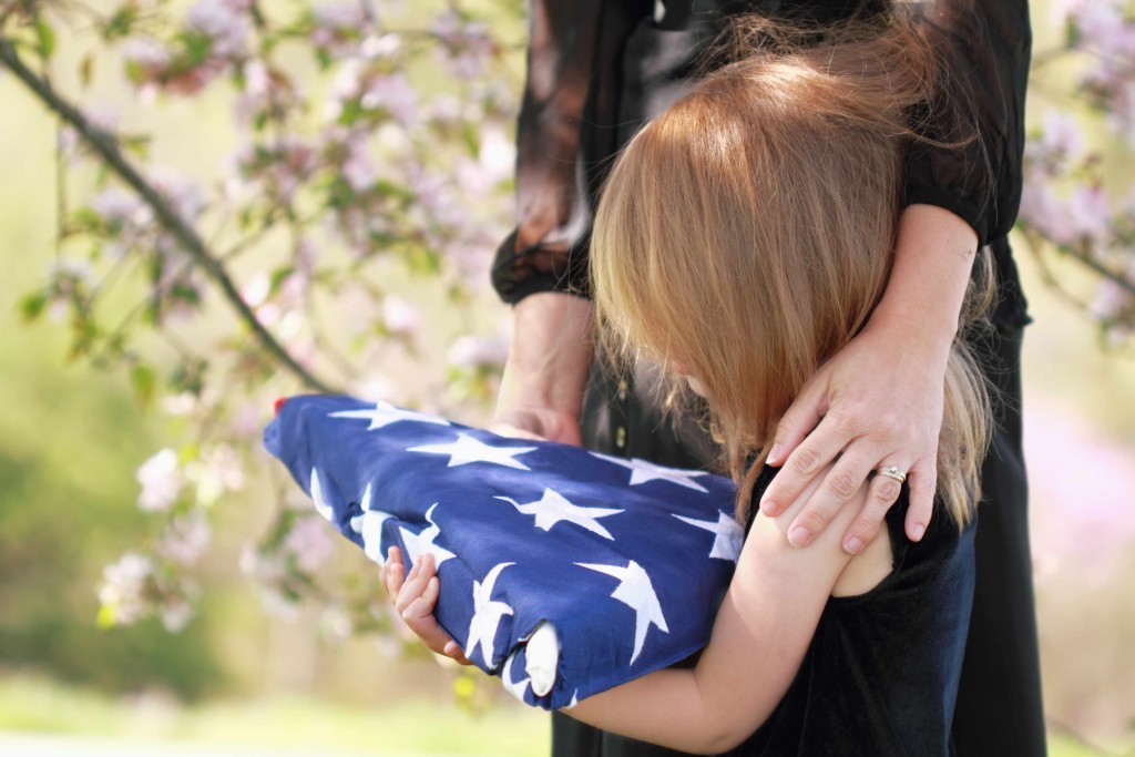 young child with mother, holding flag at grave site, sad, grief, crying, depressed