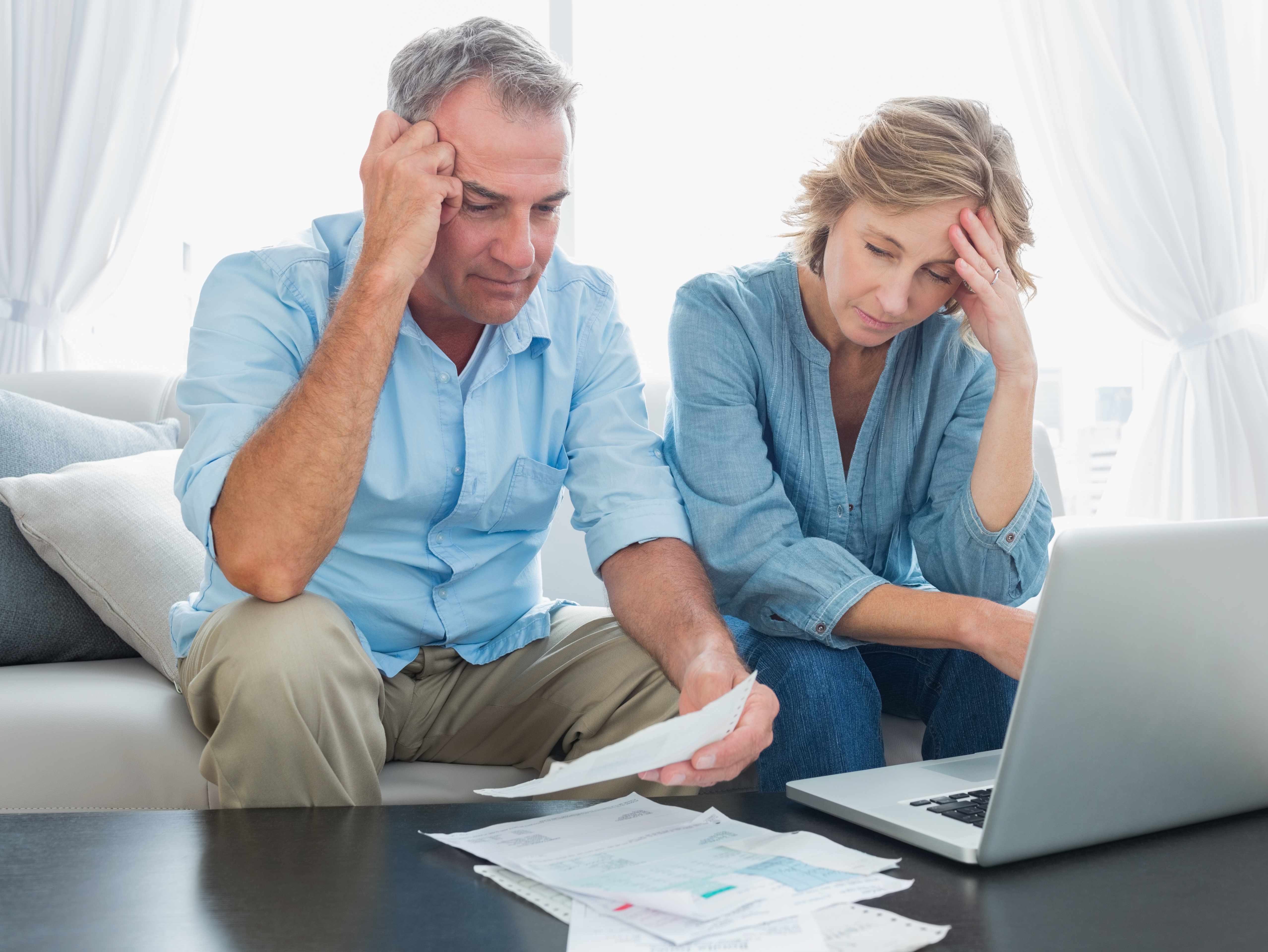 man and woman, couple, sitting at computer worried and concerned about finances