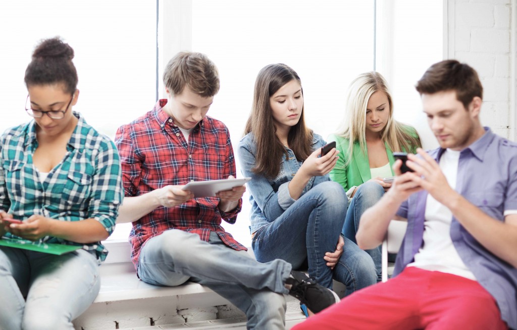 Jóvenes y adolescentes, todos usan dispositivos móviles, teléfonos celulares y mensajes de texto